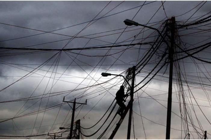 عامل يقوم بصيانة أحد أعمدة الكهرباء خلال منخفض سابق- %28أرشيفية تصوير%3A محمد أبو غوش%29